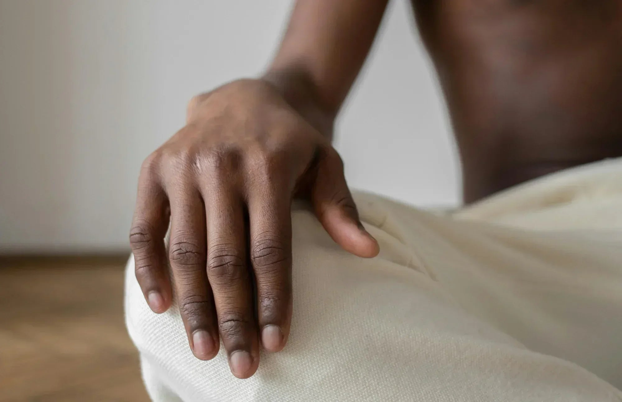 Shirtless man sitting on a bed with a relaxed expression