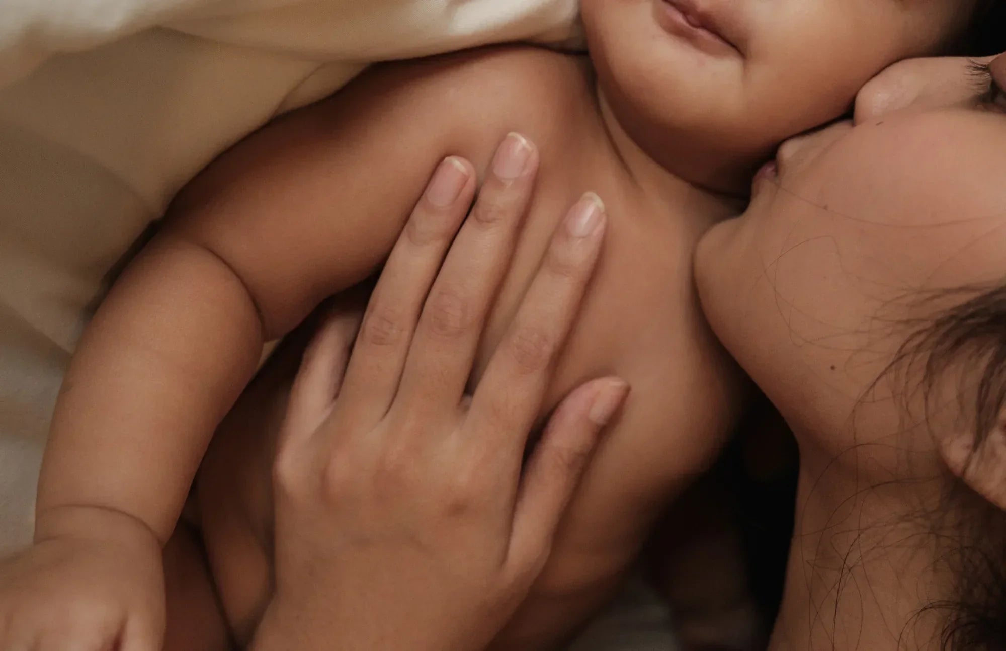 Mother gently holding her baby’s hand, illustrating a nurturing bond.