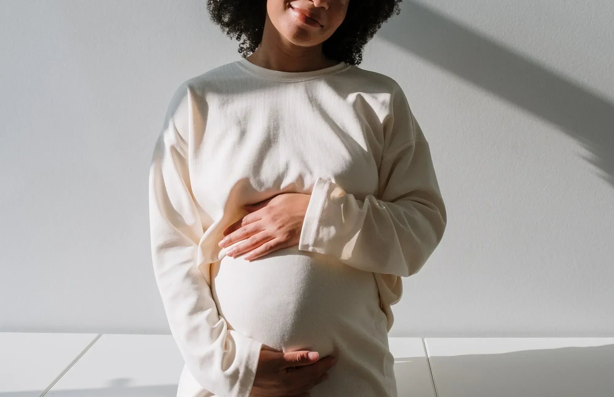 Smiling pregnant woman holding her belly, representing the benefits of taking probiotics during pregnancy for maternal and baby health