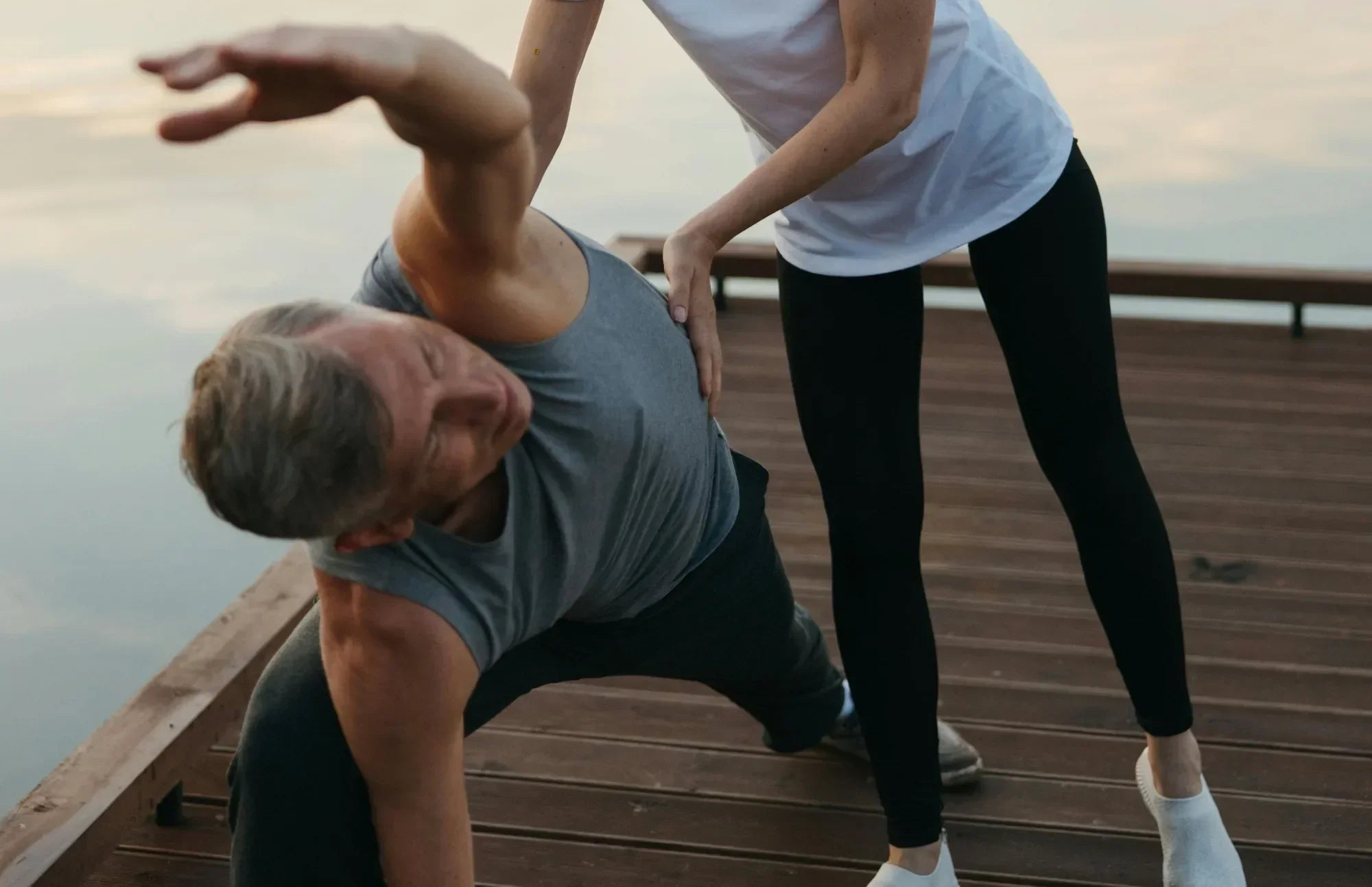 Active senior man practicing yoga with support – promoting bone strength and nutrient absorption through probiotics