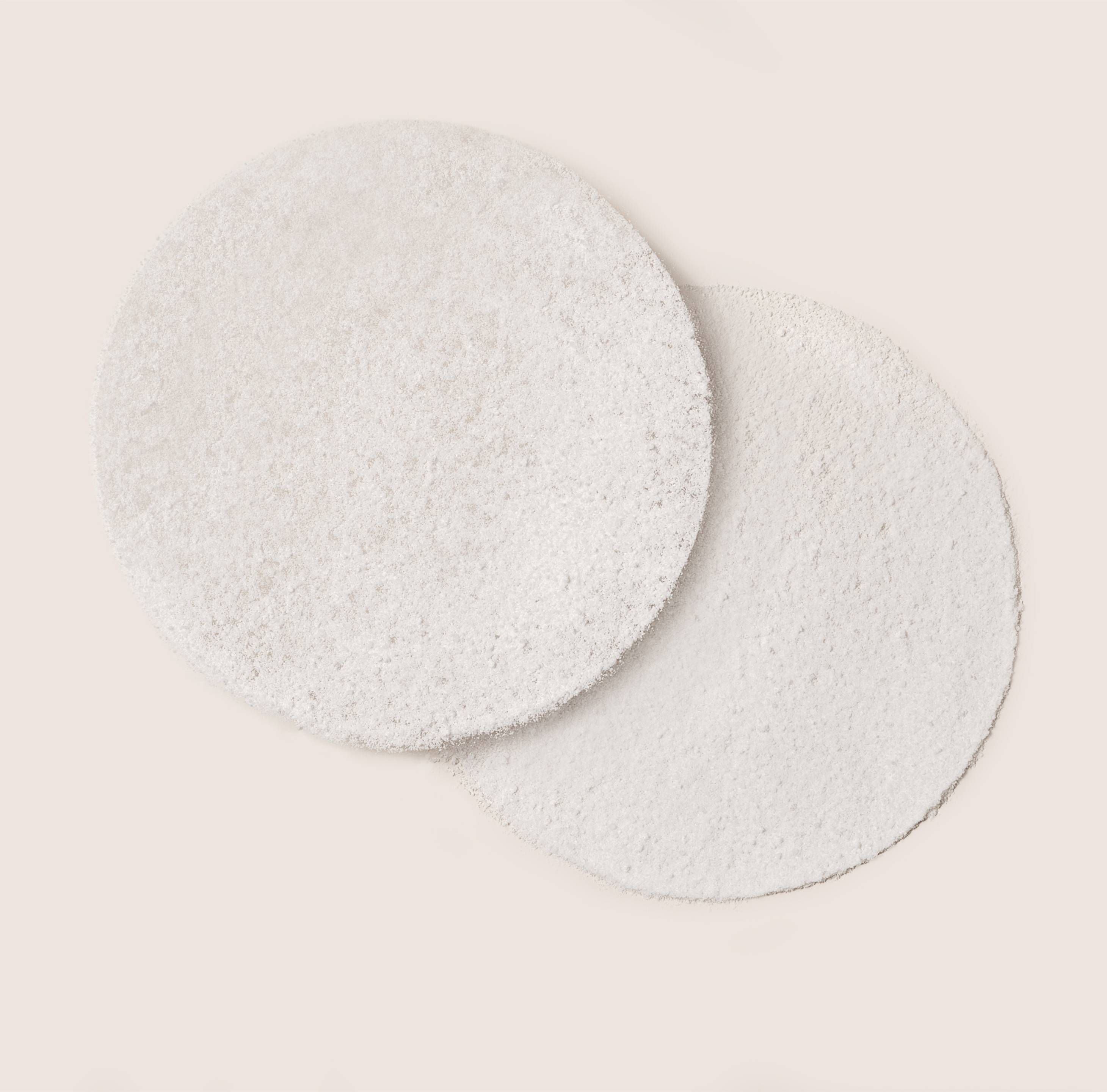 Two round pads of probiotic supplement powder, emphasizing Omni-Biotic's unique powder delivery mechanism, which ensures significantly higher probiotic survival when compared to other leading U.S. brands