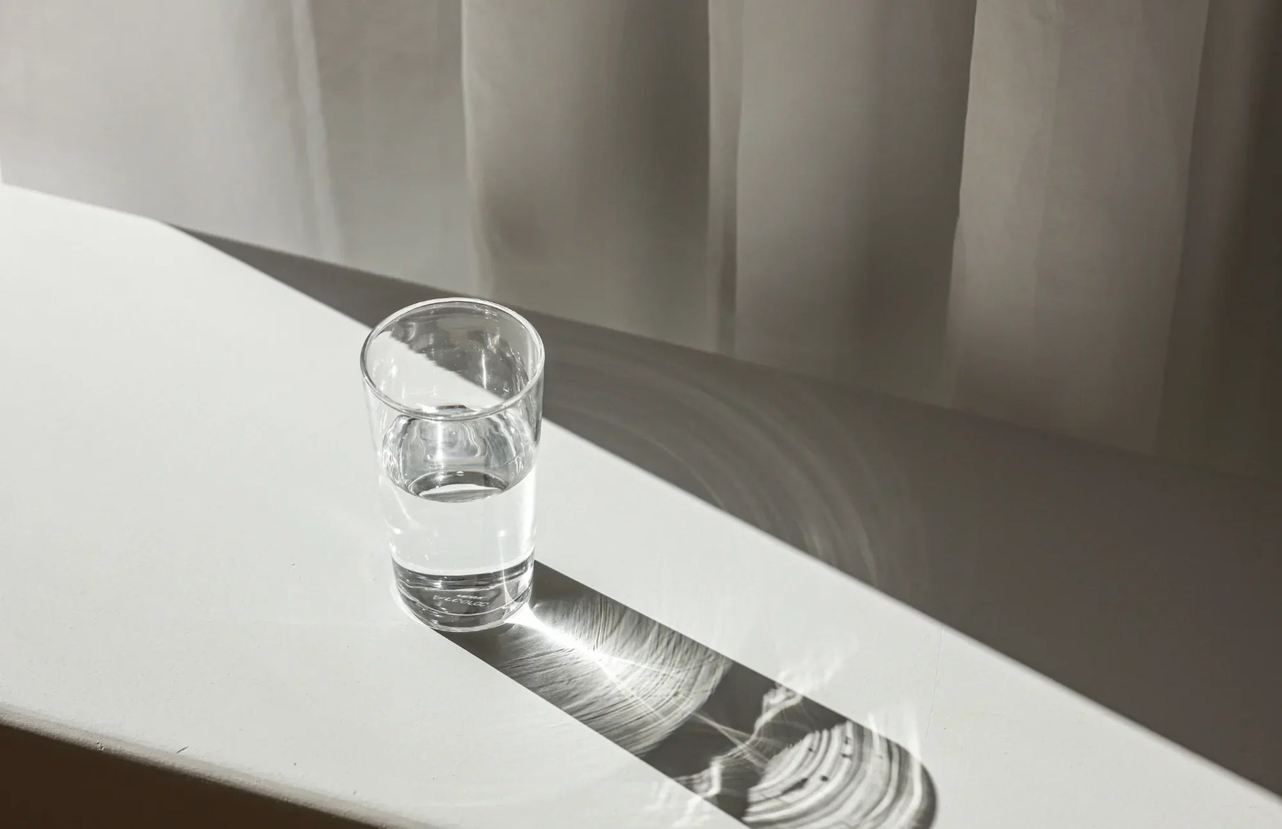 Minimalist photo of a glass of water casting a dramatic shadow—representing clarity and moderation when considering the right amount of probiotic supplementation.
