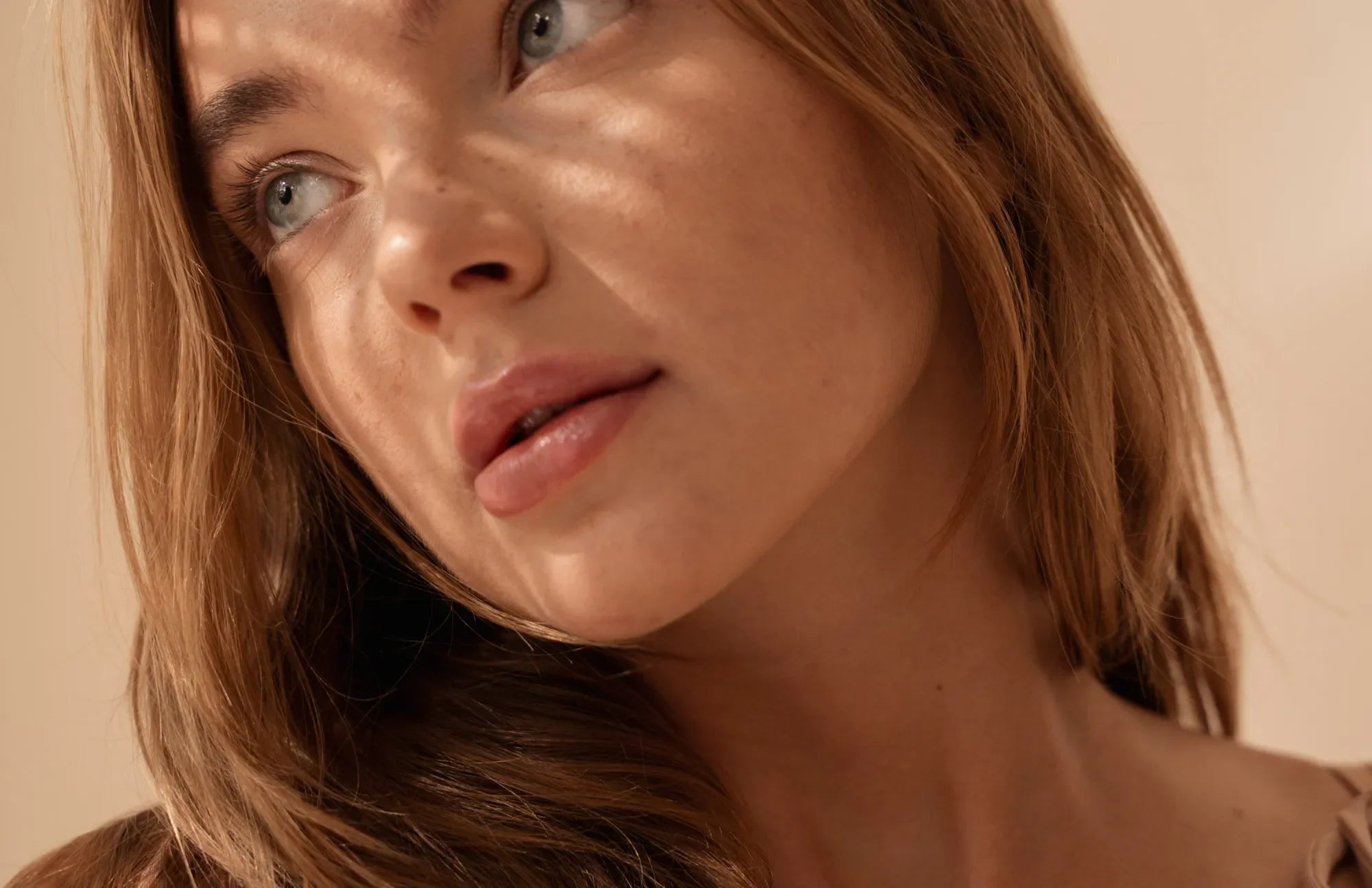 Close-up of a thoughtful woman in soft light, symbolizing the connection between gut health, mood, and mental clarity