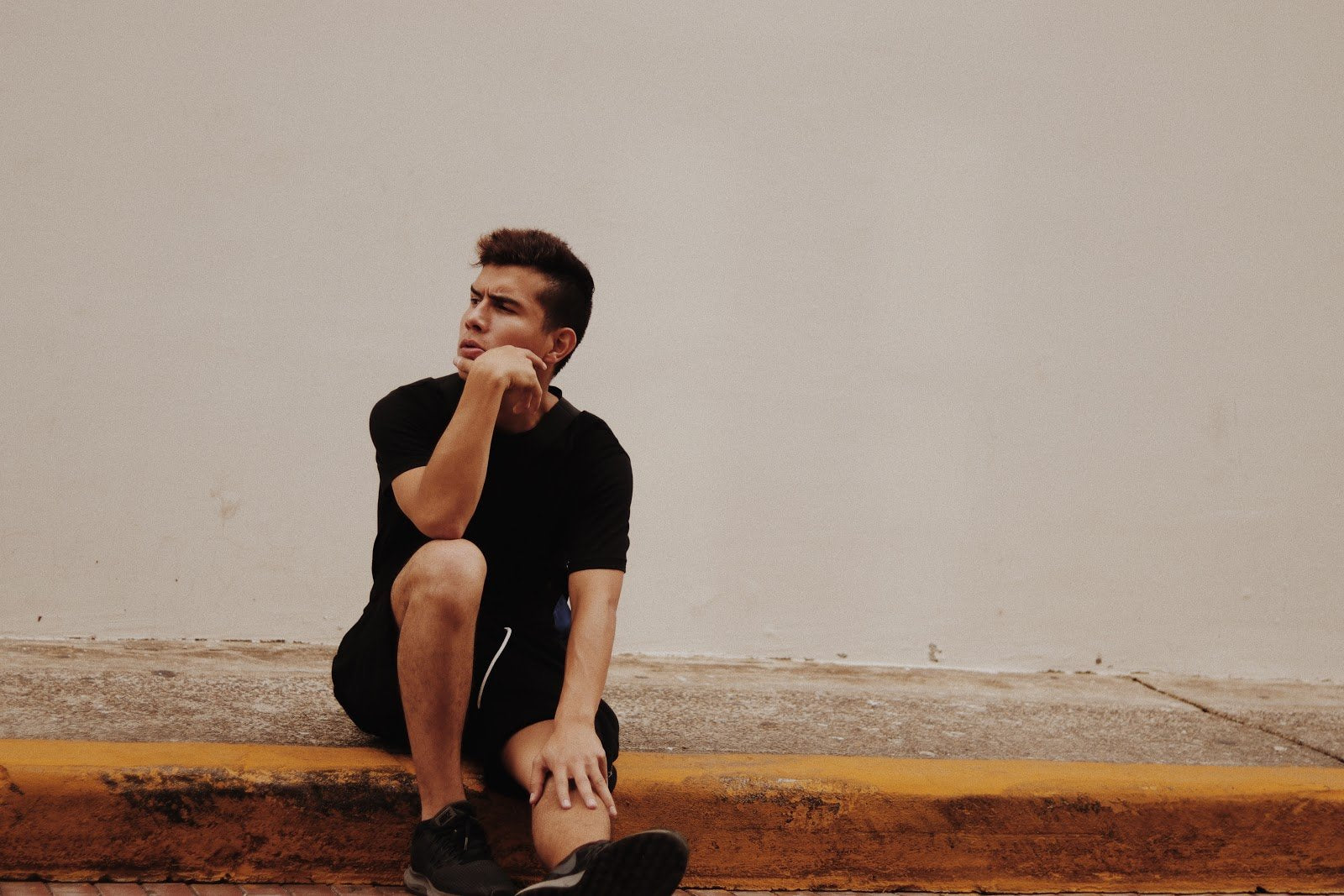photo-of-man-with-hand-on-chin-sitting-on-concrete-pavement