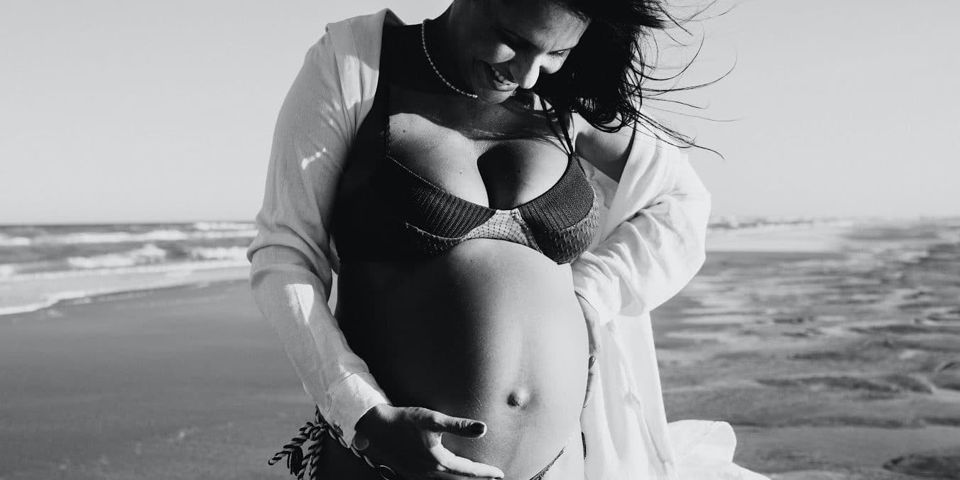 black-and-white-photo-of-pregnanct-woman-in-bikini-on-the-beach